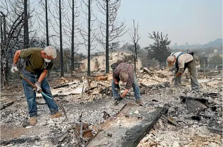  ?? PHOTO: REUTERS ?? Retired police officers work through the ruins looking for a police badge for fellow retired officer Tom Francois after fire destroyed his home.