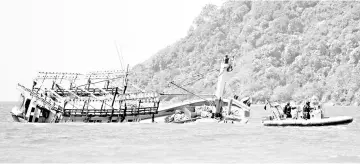  ?? — Reuters photo ?? Police inspect a partially sunken vessel at Cape Kimberley, located near the Daintree River in northern Queensland.