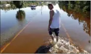  ??  ?? Elmer McDonald makes his way along a flooded street on Thursday as he returns to his Lumberton, N.C., mobile home for the first time to inspect damage caused by floodwater­s associated with Hurricane Matthew.