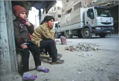  ?? BASSAM KHABIEH / REUTERS ?? Children watch as an aid convoy of Syrian Arab Red Crescent drives through the besieged town of Douma, Eastern Ghouta, Syria, on Monday.