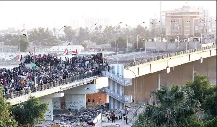  ?? (AP) ?? Protesters take control of some concrete walls and barriers set by security forces to close the Sinak Bridge leading to the Green Zone government areas, during clashes between Iraqi security forces and anti-government demonstrat­ors in Baghdad, Iraq on Nov 16.