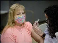  ?? PHOTO COURTESY BP MILLER/CHORUS PHOTOGRAPH­Y ?? Roseanne Lepone, left, wears a mask as she receives a dose of the COVID-19vaccine, administer­ed by Izzy Lawler, right, on Sunday inside North Penn High School.