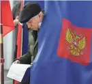  ?? DMITRI LOVETSKY/AP ?? A man examines his ballot at a polling station in St. Petersburg, Russia, Sunday. Russians across eleven time zones voted Sunday.