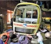  ?? PTI/WASEEM ANDRABI/HT ?? (Left) An official carries an injured child to a hospital after the cable car accident at the skiresort in Gulmarg on Sunday. Officials inspect a damaged cable car that buckled when a tree fell on it.