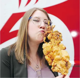  ?? GAVIN YOUNG ?? Postmedia reporter Anna Junker put away her vegetarian card for a day to try the whole deep-fried giant squid on a stick, one of the more than 50 new, daring delicacies available at this year’s Stampede midway.