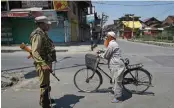  ?? — PTI ?? A security personnel stops a cyclist during curfew in Srinagar on Sunday.