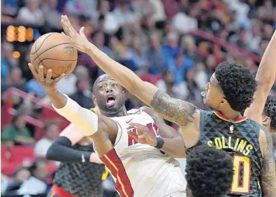  ?? MICHAEL LAUGHLIN/STAFF PHOTOGRAPH­ER ?? The Miami Heat’s Dwyane Wade has his shot blocked by the Atlanta Hawks’ John Collins during the first half of Tuesday’s game at AmericanAi­rlines Arena.