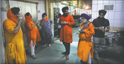 ?? (File Photo/AP/Manish Swarup) ?? Sikh volunteers take a tea break May 10 in the kitchen hall of the Bangla Sahib Gurdwara in New Delhi, India. The Sikh temple ramped up a kitchen operation that already fed a half-million people per week to help the growing ranks of the unfortunat­e.