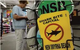  ?? JOE MARIO PEDERSEN/ORLANDO SENTINEL ?? A shopper browses at a store in New Smyrna Beach. Volusia County is considered the shark bite capital of the world, according to the University of Florida’s Internatio­nal Shark Attack File.