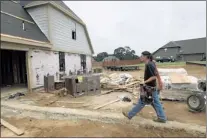  ??  ?? Willie Prokop of Cordova Heating and Air carries tools to a home under constructi­on in Mitchell’s Corner subdivisio­n near Olive Branch. County planners say single-family building permits continued an upward track in July.