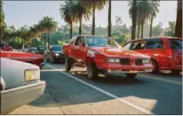  ?? ?? A refurbishe­d red classic car cruises down a Los Angeles street fringed by palm trees on Oct. 9. Before a ban on cruising in Los Angeles County was repealed, violations were punished with a fine of up to $250.