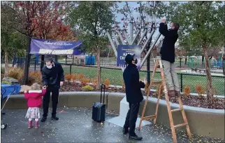  ?? PROVIDED BY ELI BECKMAN ?? Corte Madera mayor Eli Beckman, right, prepares to place a lamp on a menorah at the Town Park in Corte Madera.