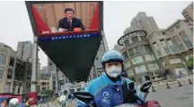  ?? ?? A delivery worker rides near a screen showing Chinese President Xi Jinping at an event celebratin­g the centenary of the Chinese Communist Youth League, Tuesday.
