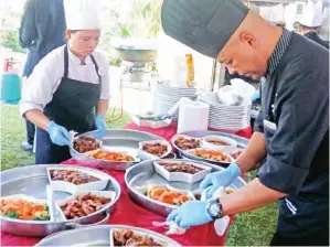  ??  ?? (Gambar atas) CHANDRAN (kanan) fokus menghidang­kan makanan.
(Gambar kanan) CHANDRAN bersama petugas dapur tersenyum lega seusai makanan siap disediakan.