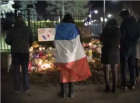  ?? JUSTIN TANG — CANADIAN PRESS VIA AP ?? A person wears a French flag at a memorial outside the French Embassy, Saturday, Nov. 14, in Ottawa, Ontario, following deadly attacks in Paris on Friday.
