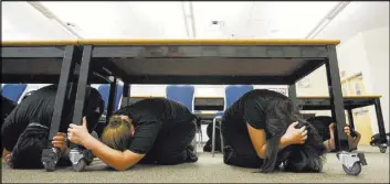  ?? Chase Stevens Las Vegas Review-Journal file ?? Students Nikki Lee, center left, and Abegayle Boro, right, drop for cover during an earthquake preparedne­ss drill in 2013.