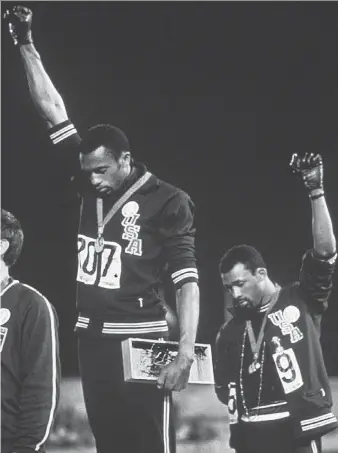  ?? THE ASSOCIATED PRESS FILE ?? An enduring image from the 1968 Summer Olympics in Mexico was that of U.S. track stars Tommie Smith, centre, and John Carlos raising their fist in protest during the playing of “The Star-Spangled Banner” after Smith received the gold and Carlos the...