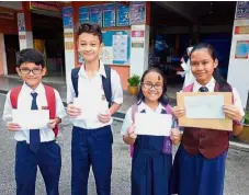  ??  ?? Young achievers: Zara (second from right) posing with other UPSR top scorers after receiving her results slip.