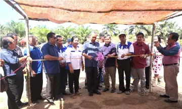  ??  ?? Penguang cuts the ribbon during the earth breaking ceremony for the building of a longhouse at Sg Pudan Rian Sebatu.