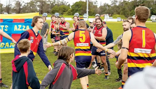  ?? Photograph­s Fearghus Browne ?? Aaron Serong heads out onto the ground surrounded bu his teams mates as he prepares to run through a banner marking his 250th game for Longwarry. He put in a strong perfomance kicking two goals against Catani.