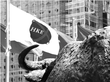  ?? PHOTO: REUTERS ?? SHORT-TERM SURGE A flag of the Hong Kong Stock Exchange flies outside the Exchange Square business tower. In the short term, Hong Kong markets can expect an increase in volatility as hundreds of millions ofmainland traders start heading Hong Kong’s...