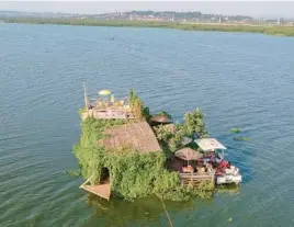  ?? PATRICK ONEN/AP ?? A floating restaurant and bar is seen from the air Feb. 18 in Lake Victoria near the Luzira area of Kampala, Uganda. Flowering plants rise from the water into the hull.