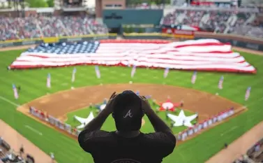  ?? ASSOCIATED PRESS FILE PHOTO ?? A spectator takes a photo of a United States flag as it is unveiled for the national anthem as part of Military Appreciati­on Day before a baseball game between the Atlanta Braves and the Washington Nationals in Atlanta on May 20.