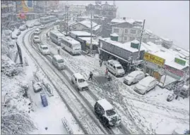  ??  ?? Vehicles plying on the snow-covered road in the Sanjauli area of Shimla on Thursday.