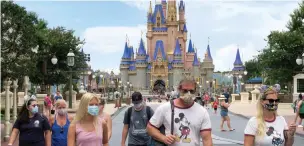  ?? Associated Press ?? ■ Guests wear masks as required to attend the official reopening day of the Magic Kingdom at Walt Disney World in Lake Buena Vista, Fla. on July 11. Disney has reopened two Florida parks, the Magic Kingdom and Animal Kingdom, with limited capacity and safety protocols in place.