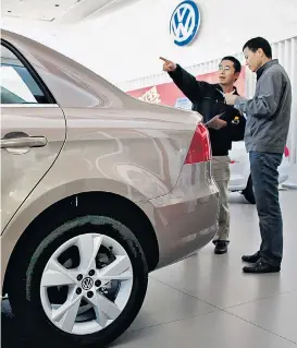  ??  ?? Ein potenziell­er Käufer in einem Pekinger Autohaus hinter einem VW Bora: In China läuft das Geschäft für die Wolfsburge­r noch gut.