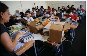  ?? AP/HUSSEIN MALLA ?? Palestinia­n refugee students receive new books Monday as they begin the school year at a Beirut school supported by the United Nations Relief and Works Agency.