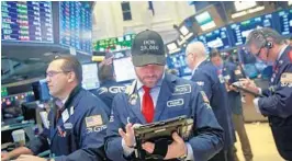  ?? DREW ANGERER/GETTY IMAGES ?? A trader wearing a ‘Dow 25,000’ hat works on the floor of the New York Stock Exchange (NYSE) ahead of the closing bell on Thursday.