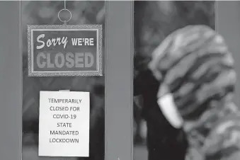  ??  ?? A pedestrian walks by The Framing Gallery, closed due to the COVID-19 pandemic, Thursday, in Grosse Pointe, Mich. [PAUL SANCYA/ THE ASSOCIATED PRESS]