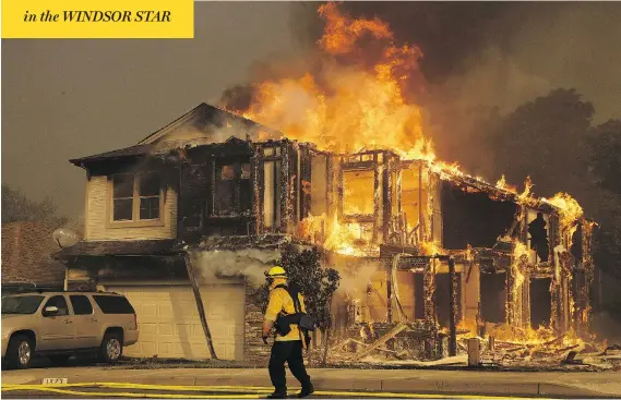  ?? JEFF CHIU / THE ASSOCIATED PRESS ?? A firefighte­r walks by an engulfed home in Santa Rosa, Calif., on Monday as wildfires swept through Northern California, killing at least 10 and destroying 1,500 homes.