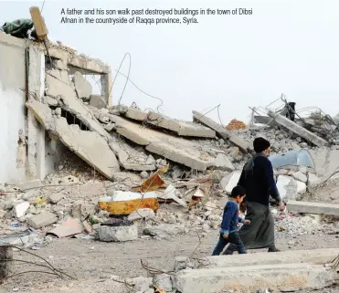  ??  ?? A father and his son walk past destroyed buildings in the town of Dibsi Afnan in the countrysid­e of Raqqa province, Syria.