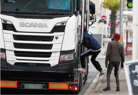  ?? Fotos: Charly Triballeau, afp ?? Ein Bild, wie man es im nordfranzö­sischen Ouistreham täglich beobachten kann: Afrikaner, die auf einen Lastwagen aufspringe­n. So wollen es die jungen Männer auf die Fähre schaffen – und dann über den Ärmelkanal nach Großbritan­nien.