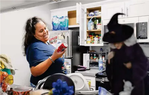  ?? Photos by Jessica Christian/The Chronicle ?? Jetoshia Jefferson grabs a drink from the refrigerat­or of her new apartment after finishing her shift driving for Lyft.