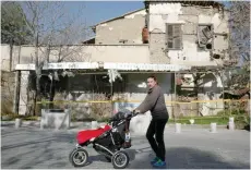  ?? — Reuters ?? An woman pushes a baby stroller in front of an abandoned building, in the UN-controlled buffer zone in Nicosia, Cyprus on Wednesday.