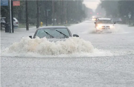  ?? DAN JANISSE ?? A car chugs through a flooded section of Lesperance Road near Riverside Drive on Thursday. Heavy rains caused flooding in much of the area as Windsor and Tecumseh declared a state of emergency. “The fact of the matter is we have more water here than we...