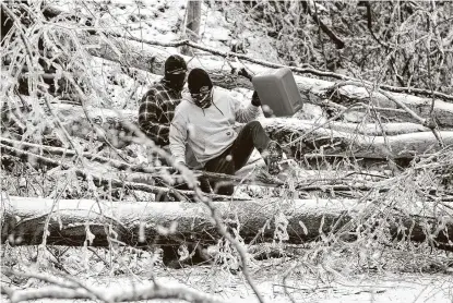  ?? Sholten Singer / Associated Press ?? Two men climb over downed trees as they head out to retrieve gas for generators Tuesday in Huntington, W.Va. Winter weather paralyzed large swaths of the United States, and many people are without electricit­y following the storms.