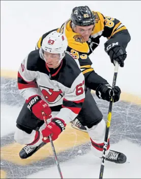  ?? STUART CAHILL / BOSTON HERALD FILE ?? Boston’s Karson Kuhlman reaches around New Jersey’s Jesper Bratt at the Garden on Sept. 25, 2019.