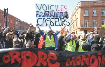  ??  ?? French activist Jean-Baptiste Redde, aka Voltuan (centre), holds a placard reading “here are the troublemak­ers” with the pictures of French politician­s as ‘Yellow vests’ protesters take to the streets for the 22nd consecutiv­e last Saturday in Toulouse. — AFP photo