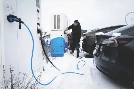  ?? SERGEI GRITS/AP ?? A DRIVER CHARGES AN ELECTRIC CAR at a parking lot of a shopping mall in Tallinn, Estonia, on Feb. 11,. Many electric vehicle batteries lose power when it’s very cold.