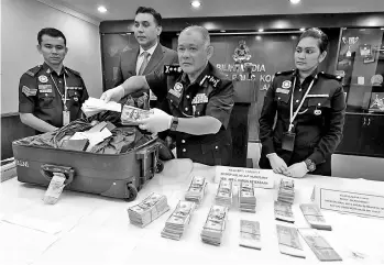  ??  ?? Negeri Sembilan police chief Datuk Noor Azam Jamaludin (second, right), showing the seized counterfei­t RM100 and USD100. A total of 10.91 grammes of syabu were also found in the operation named‘Ops Khas’.Three men and two women were detained by the...