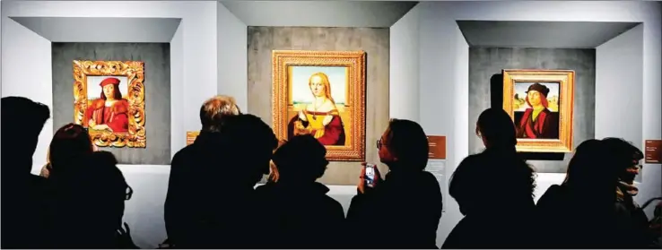  ?? AFP ?? Visitors look at the paintings (from left to right) Young Man with an Apple, Young Woman with Unicorn and Portrait of a Man by Renaissanc­e master Raffaello.