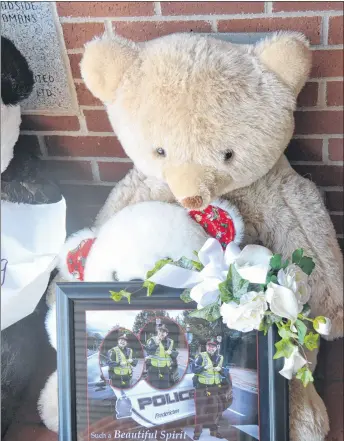  ?? STU NEATBY/THE GUARDIAN ?? A monument to the four Fredericto­n residents killed in a shooting Friday morning steadily grew over the course of the weekend. This teddy bear and photo pays tribute to police constable Sara Mae Burns, who her family said in a statement “absolutely loved her job, and went to work each shift committed to serving this great community.”