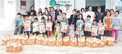  ??  ?? BANTUAN: Chew (belakang tengah) bersama Kelvin serta yang lain merakam kenangan bersama keluarga penerima bantuan bersama anak-anak yang berupa alat tulis serta beras.