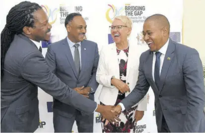  ?? (Photo: Micheal Sloely/jis) ?? State minister in the Ministry of Education, Youth and Informatio­n, Floyd Green exchanges a hearty greeting with Senator Damion Crawford (left) during the Poverty Reduction Programme’s Youth Forum on Thursday at Mona Visitors’ Lodge in St Andrew. Sharing the moment are managing director of Jamaica Social Investment Fund, Omar Sweeney and head of the European Union Delegation to Jamaica, Ambassador Malgorzata Wasilewska.