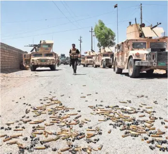  ?? MAHMOUD ALL-SAMARRAI, AFP/GETTY IMAGES ?? Shell casings litter the ground as Iraqi government forces gather around the Qaiyara air base near Mosul that was seized from the Islamic State by Iraqi forces.