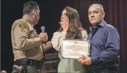  ?? Photograph­s by Irfan Khan Los Angeles Times ?? SHERIFF ROBERT LUNA presents a certificat­e for Alex Martinez, critically injured in a November car crash during training, to the recruit’s sister and father.